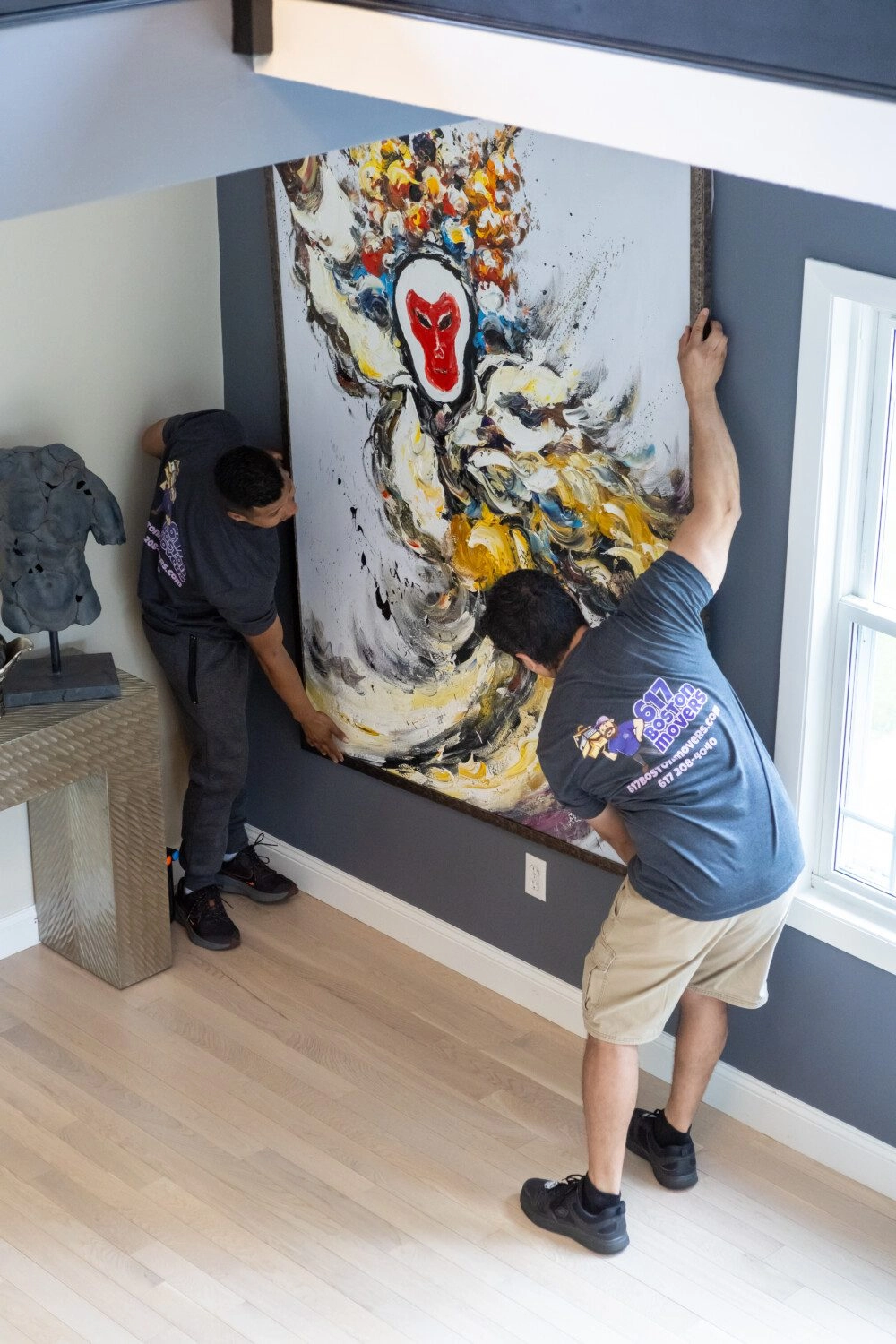Boston movers hanging a large piece of art on a wall