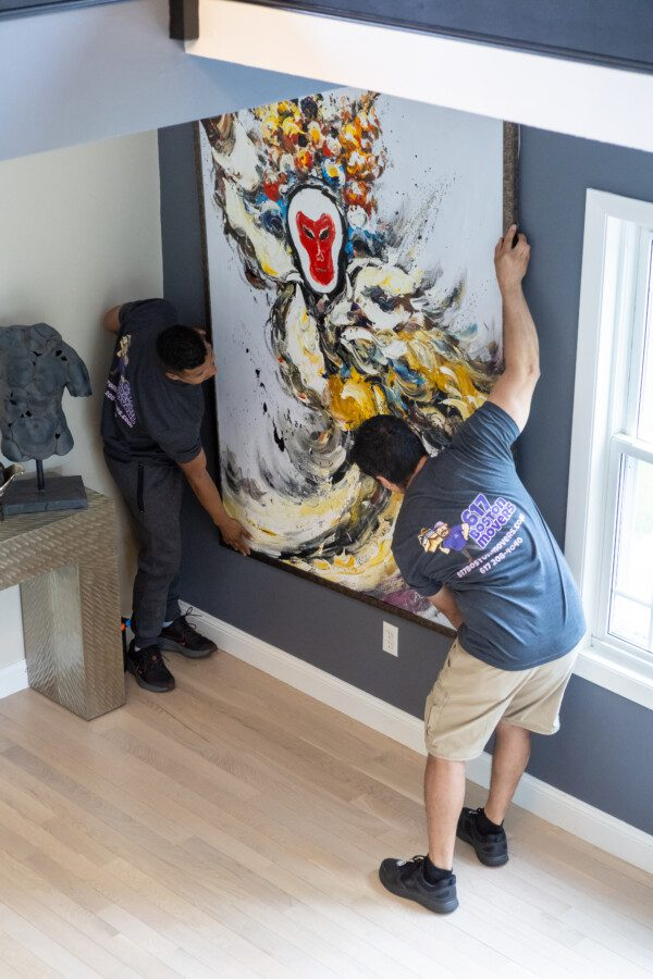 Boston movers hanging a large piece of art on a wall