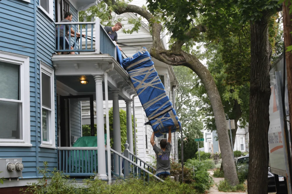 Boston movers hoisting a couch up to a balcony