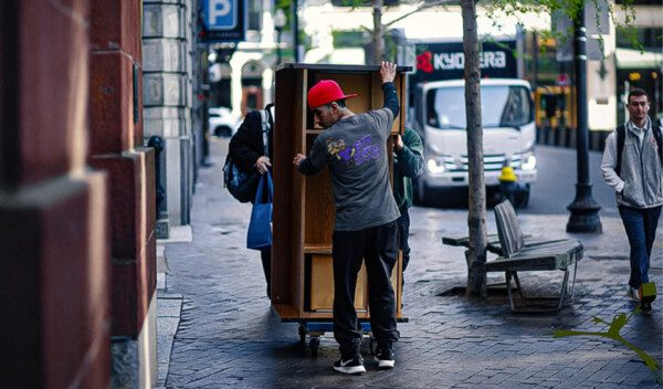 Mover guiding an office cabinet along a downtown sidewalk